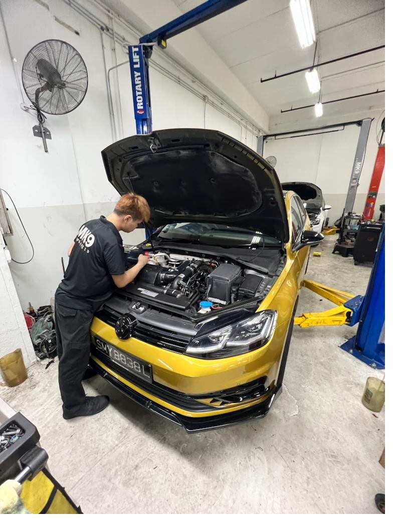 Mechanic working on a yellow Golf engine bay